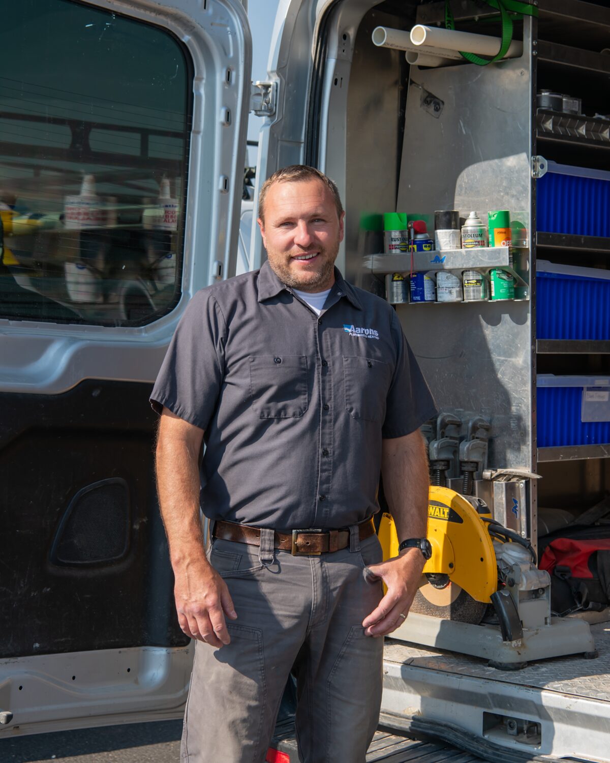 Aaron Clark, owner of Aaron's Plumbing & Heating, standing at his fully stocked work van